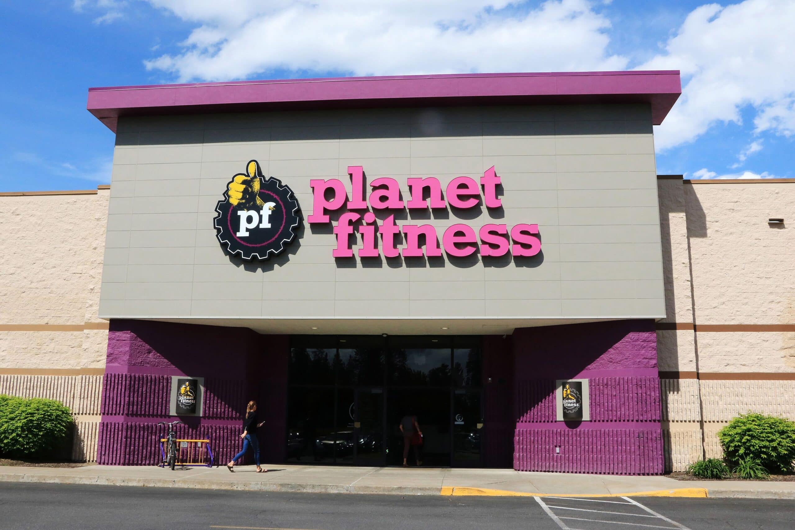 Brightly lit Planet Fitness gym exterior with pink and purple branding, showcasing a modern fitness center promoting health, wellness, and physical activity for all fitness levels.